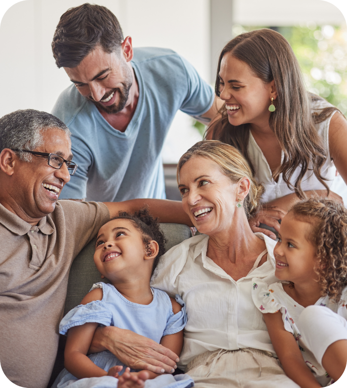 A multi-generational family smiling and enjoying each other's company indoors.
